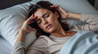 © Анатолий - Woman Lying in Bed Feeling Unwell and Holding Her Forehead in Discomfort