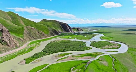 Wall Mural - Curved river and green grassland with mountain natural landscape in Xinjiang. Famous grassland pasture scenery in China.