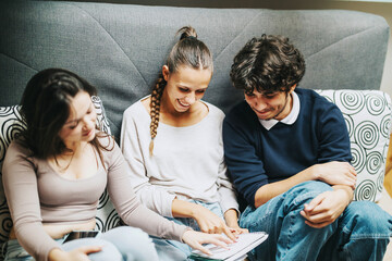 Poster - Three young students collaborate on a project while sitting comfortably on a couch. They appear engaged and focused, fostering a sense of teamwork and shared learning in a relaxed environment.