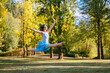 © Connect Images - Joyful ballerina dancing outdoors in a park with autumn trees in the background.