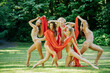 © Connect Images - A group of five dancers poses artistically in a park with a red fabric, wearing beige leotards, USA
