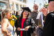 © Connect Images - Smiling woman in graduation gown and cap holding flowers and a diploma celebrates with family outdoors on a sunny day, Bournemouth, Dorset UK
