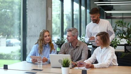 Wall Mural - Successful businesspeople working in a coworking space working with laptop discussing strategy and business plan in modern office.