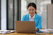 © Wasan - Asian business woman wearing glasses Working with tablet and documents at desk in office