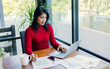 © Thawatchai Images - Business women wearing red sweater working about new startup on laptop to analysis finance of project in outside office, Woman working using laptop online meeting in home office.