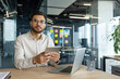 © Liubomir - A confident businessman holds a tablet while sitting at a desk in a modern office. The scene epitomizes professionalism, work, and success, with a laptop and decor enhancing the workplace ambiance.