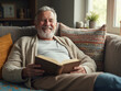 © Experimential - Happy senior man smiling while reading a book on the sofa at home
