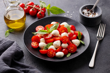 Wall Mural - Caprese salad with tomatoes, mozzarella cheese, basil. Grey background. Close up.