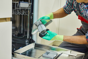 An Appliance Repair Technician is servicing a dishwasher in a modern kitchen. A skilled technician is repairing a modern dishwasher