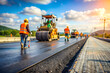© Kymaka28 - background of construction site is laying new asphalt road pavement, road construction workers and road construction machinery scene.highway construction site landscape