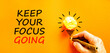 © Dzmitry - Keep your focus going symbol. Concept words Keep your focus going on beautiful orange paper. Beautiful orange background. Businessman hand. Business and keep your focus going concept. Copy space.
