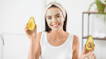 Wall Mural - Beautiful young woman with facial mask and avocado in bathroom