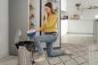 © Pixel-Shot - Young woman throwing spoiled mushrooms into trash bin near open fridge in kitchen