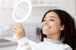 © Prostock-studio - Happy Black Female Patient Looking At Mirror After Dental Treatment In Clinic, Cheerful African American Woman Sitting In Chair In Stomatological Cabinet And Enjoying Her Beautiful Smile, Closeup