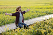 © kamonrat - Farmer Embracing Nature in Paddy Field, Joyful Celebration of Abundance and Connection to Agriculture, Kneeling on Bamboo Pathway Surrounded by Lush Green Rice Plants Under a Clear Sky