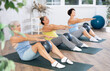 © JackF - Calm mature woman doing pilatess sitting on black mat with soft ball between legs during workout session