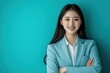 © khalid_spk - Young Asian woman, professional attire, blue button-up shirt black skirt round glasses confident smile arms crossed office building background