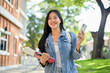 © bongkarn - A smiling Asian female college student on her way to class in the morning, holding her smartphone.