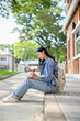 © bongkarn - A positive Asian female student sits on the edge of a footpath at her university, writing in a book.