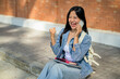 © bongkarn - An excited and happy Asian female college student receives good news over the phone.