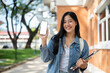 © bongkarn - A beautiful college student showing her smartphone to the camera while standing at the university.