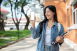 © bongkarn - A beautiful college student showing her smartphone to the camera while standing at the university.