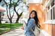 © bongkarn - A cheerful Asian female college student on her way to class, smiling at the camera.