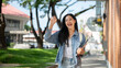 © bongkarn - A cheerful Asian female college student waves to her friends while walking on her way to class.