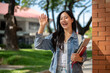 © bongkarn - A cheerful Asian female college student waves to her friends while walking on her way to class.