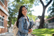 © bongkarn - A cheerful Asian female college student on her way to class, smiling at the camera.