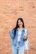 © bongkarn - A cheerful Asian female college student shows a victory fist, receiving good news through a message.
