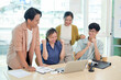 © bongkarn - A cheerful young adult Asian business startup team celebrates their good news together.