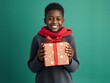 © kengkreingkrai - smiling boy holding a present wrapped in red ribbon and a red bow.