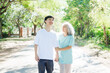 © NanSan - A happy senior mother embraces her smiling adult son in a lush green park. Surrounded by nature, their affectionate hug symbolizes love, peace, vitality, and renewal under the serene greenery