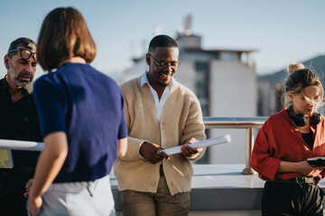 Canvas Print - A diverse group of business associates brainstorming and analyzing project plans on a rooftop. Multiracial employees collaborate in an outdoor setting, discussing innovative ideas and business