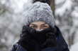 © Cavan Images - Closeup of young woman in scarf and hat covered in snow