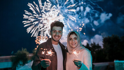 Wall Mural - photo of a couple holding sparklers with fireworks background