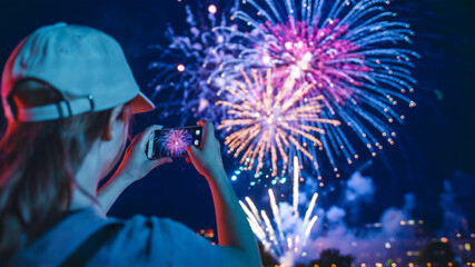 Wall Mural - photo of holding a smartphone, capturing a vibrant display of fireworks