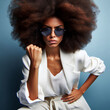 © Moiss - Esta mujer enojada tiene un peinado afro, aprieta los dientes por ira, mira con odio, frunce el ceño, usa gafas de sol y ropa blanca informal, modela sobre fondo azul y expresa odio.