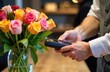 © YULIA - Payment for a bouquet of flowers through a terminal in a store. Modern technologies in the flower business. The concept of preparing for a holiday in flower shops
