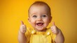 © imagineRbc - A cheerful baby with a wide smile gives two thumbs up while wearing a yellow outfit. The vibrant yellow background enhances the joyful atmosphere and playful mood