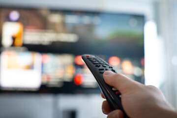 person changing tv programs by using smart tv remote control. close up view.