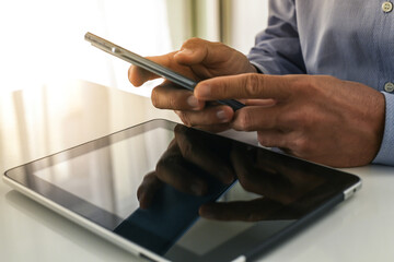 Wall Mural - Closeup man hands using smartphone. Businessman works with tablet and mobile phone. Office workplace