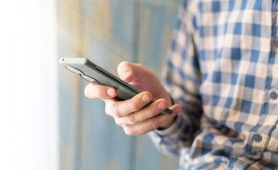 Close-up image of male hands using smartphone at night on city shopping street, searching or social networks concept