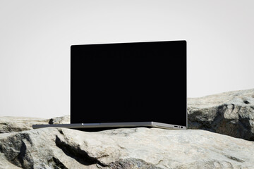 Wall Mural - scene with a opened laptop with a blank screen on the rock