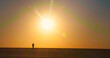 © RecCameraStock - Extreme wide shot of tourist male walking backwards the sunset in desert. Sunset light in the dark and a man silhouette having a walk in sahara.