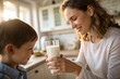 © Nelly - Close-up of a mom offering a glass of milk to her child, both smiling.