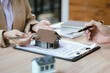 © Witoon - Businessman and real estate agents discussing documents signing a legal purchase of a house.