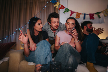 Poster - A group of friends enjoy a lively birthday celebration indoors with decorations. They are sitting on a couch, surrounded by cheerful ambiance, sharing laughter and drinks.