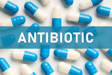 Wall Mural - Word Antibiotic and pills on white background, top view